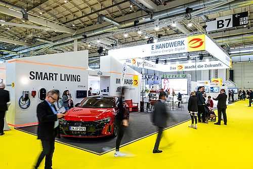 Ein Foto von der Messe GET Nord mit mehreren Ausstellerständen im Hintergrund und unscharfen Besuchern im Vordergrund, darunter ein roter Audi